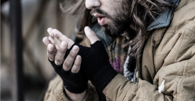 Sans-abri soufflant sur ses mains à cause du froid