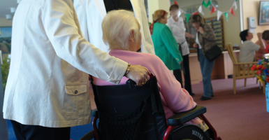 Personne senior poussée sur une chaise roulante dans une maison de repos