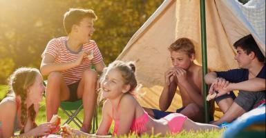 Enfants qui campent ensemble près d'une tente. 