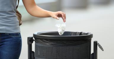 Personne qui jette son déchet à la poubelle