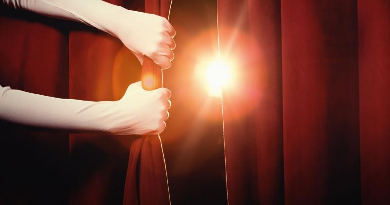 mains qui ouvrent un rideau de théâtre