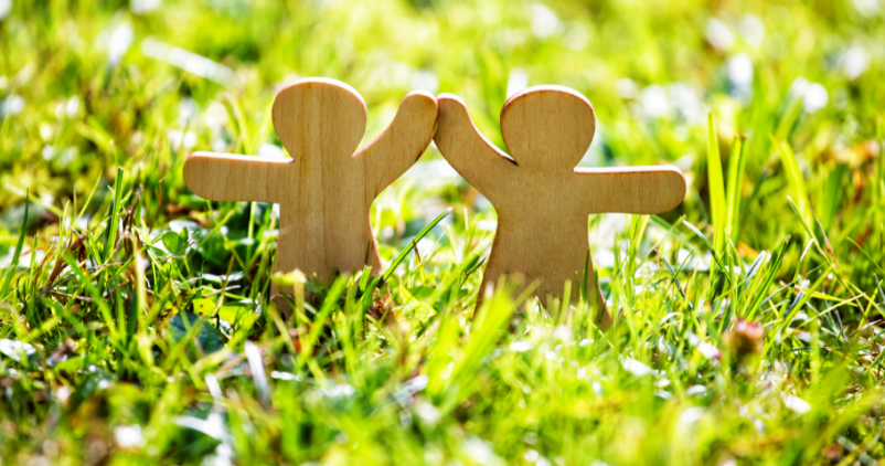 Figurines en bois qui se tapent dans la main dans l'herbe