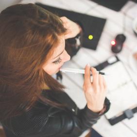 Jeune femme en train de réfléchir devant un carnet de notes